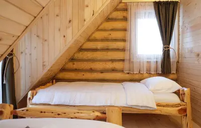 a bed in a log cabin with a staircase at Drvena Kuca RUŽA in Kopaonik
