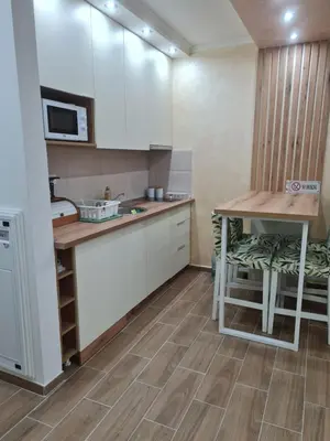 a kitchen with white cabinets and a table and a microwave at SWAN Kopaonik in Kopaonik