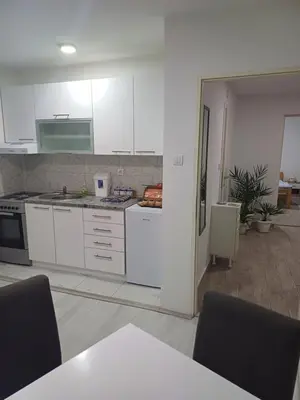 a kitchen with white cabinets and a table with chairs at Apartman “Sanja” in Pirot
