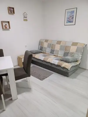 a couch in a living room with a table and a chair at Apartman “Sanja” in Pirot