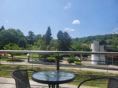 a glass table and two chairs on a balcony at Apartman Nice in Vrnjačka Banja