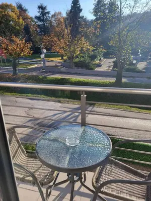 a glass table and two chairs on a patio at Apartman Nice in Vrnjačka Banja
