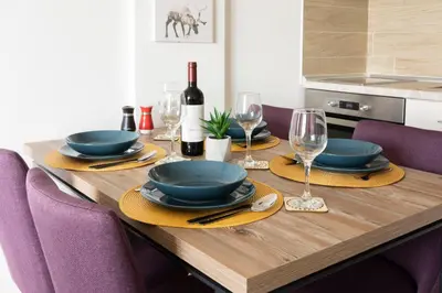 a wooden table with plates and wine glasses at Sunset View Ski & Spa apartments Kopaonik in Kopaonik