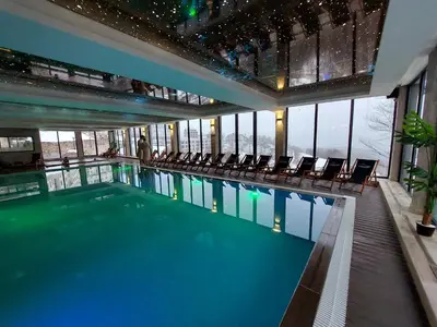 a large swimming pool with chairs in a building at Sunset View Ski & Spa apartments Kopaonik in Kopaonik