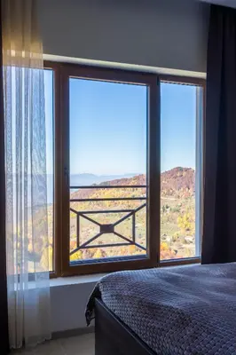 a bedroom with two large windows with a view at Sunset View Ski & Spa apartments Kopaonik in Kopaonik