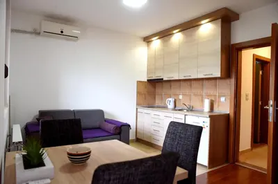 a living room with a table and a kitchen at Apartman Kentaur Vrnjačka Banja in Vrnjačka Banja