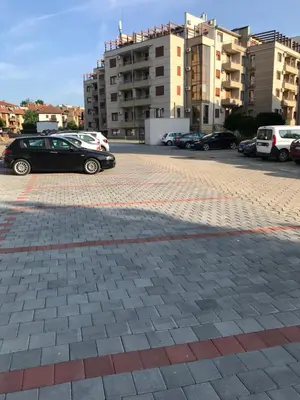 a black car parked in a parking lot with buildings at Apartman Kentaur Vrnjačka Banja in Vrnjačka Banja