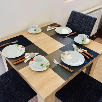 a wooden table with plates and utensils on it at Apartman Kentaur Vrnjačka Banja in Vrnjačka Banja