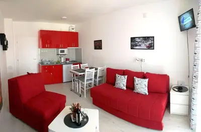 a living room with a red couch and a kitchen at Studio La Casa in Soko Banja