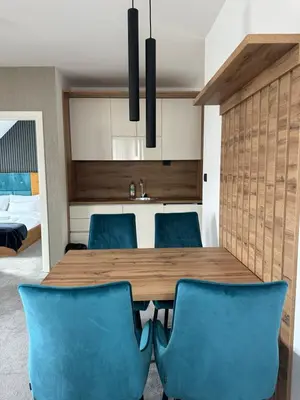 a dining room with a wooden table and blue chairs at Hotel Djina - Kopaonik in Kopaonik