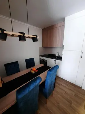 a kitchen with a dining room table and blue chairs at Apartman Radmila in Kopaonik