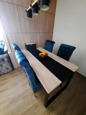 a dining room table with blue chairs and an orange on it at Apartman Radmila in Kopaonik