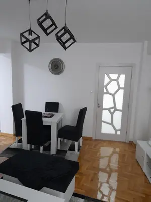 a living room with a table and chairs and a window at Holiday apartments in Niš