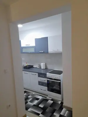 a kitchen with white cabinets and a stove top oven at Holiday apartments in Niš