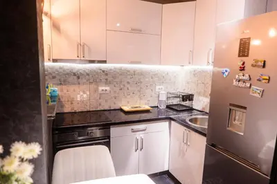a kitchen with white cabinets and a black counter top at Apartmani Đorđević in Soko Banja