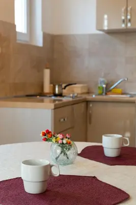 two cups and a vase with flowers on a table at Apartment Joy by Central in Vrnjačka Banja