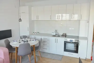 a kitchen with white cabinets and a table and chairs at Apartmani Martenovic in Vrnjačka Banja
