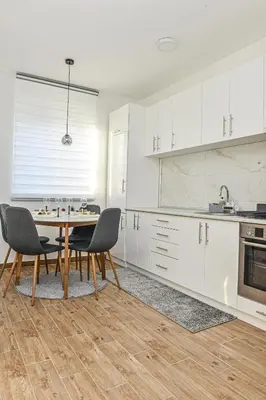 a kitchen with white cabinets and a table and chairs at Apartman Martenovic 2 in Vrnjačka Banja