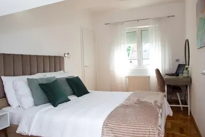 a bedroom with a large white bed with green pillows at Apartman MIA Centar in Kruševac