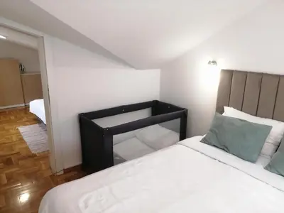 a bedroom with a bed with white sheets and blue pillows at Apartman MIA Centar in Kruševac