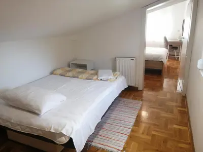 a bedroom with a large white bed and a wooden floor at Apartman MIA Centar in Kruševac