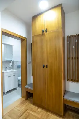a large wooden cabinet in a room with a bathroom at Apartman Bonaca in Vrnjačka Banja