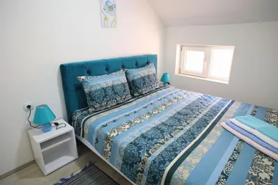 a bedroom with a blue bed and a window at Apartmani Đorđević in Soko Banja