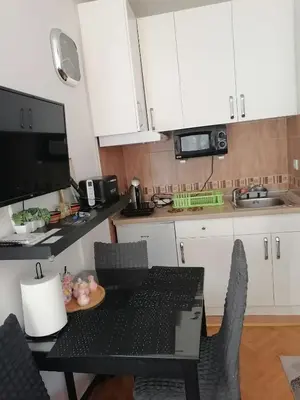 a kitchen with white cabinets and a table and chairs at Apartman Lala in Vrnjačka Banja