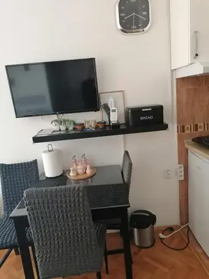 a kitchen with a table with a television on a wall at Apartman Lala in Vrnjačka Banja
