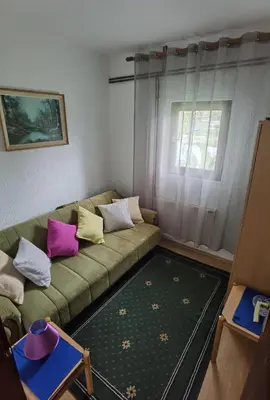 a living room with a green couch with colorful pillows at Apartmani Trio in Soko Banja