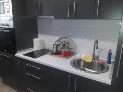 a kitchen counter with a sink and black cabinets at Aurora in Kruševac