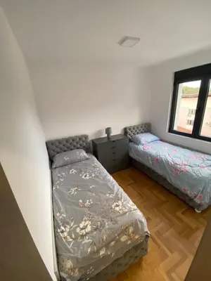 a bedroom with two beds and a window at Maya apartman sa dve spavace sobe in Vrnjačka Banja