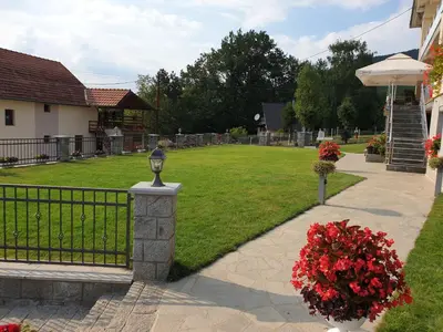 a garden with a fence and flowers in a yard at Apartman Djekovic in Jošanička Banja