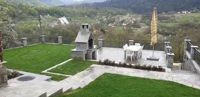 a garden with a table and a flag on a balcony at Apartman Djekovic in Jošanička Banja