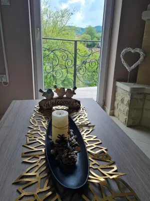 a candle on a plate on a table in front of a window at Apartman ALEX LUX in Vrnjačka Banja