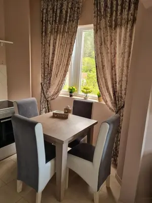 a dining room table with chairs and a window at Apartman ALEX LUX in Vrnjačka Banja
