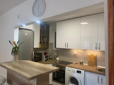 a kitchen with white cabinets and a clock on the wall at Sandra in Niš