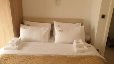 a bed with white pillows and towels on it at J&A Apartman in Jagodina