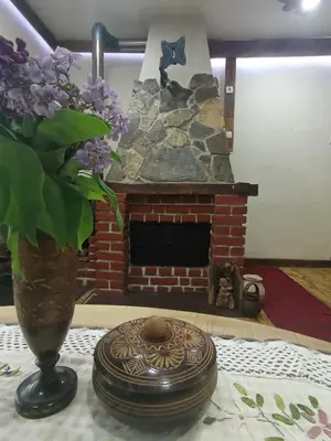 a vase of lilacs sitting on a table with a fireplace at Konaciste Mali Izvor in Boljevac