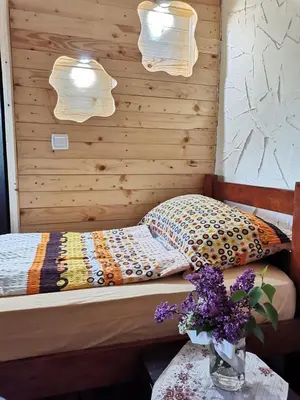 a bedroom with a bed and a vase of flowers on a table at Konaciste Mali Izvor in Boljevac
