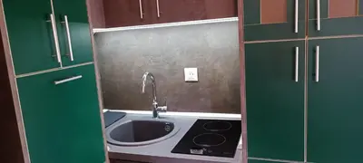 a small kitchen with a sink and green cabinets at Tajna037 in Kruševac