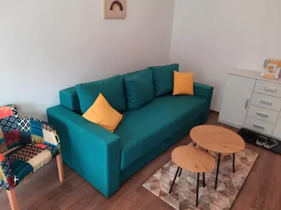 a living room with a green couch and two tables at Apartman Vista in Soko Banja