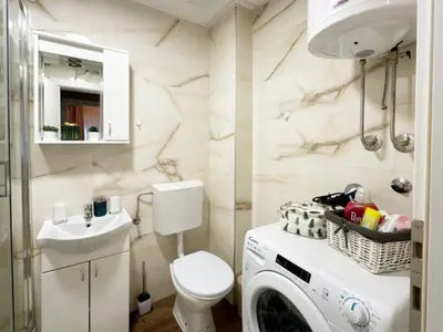 a bathroom with a toilet and a washer and dryer at Apartman Elena 11 in Vrnjci