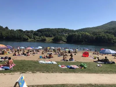 a group of people laying on the beach at a lake at Apartmani Plaža in Bor