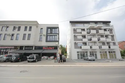 a tall building with cars parked in a parking lot at Apartman Jocić in Vrnjačka Banja