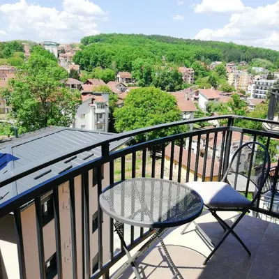 a table and chair on a balcony with a view at Apartman Ljubičica in Vrnjačka Banja