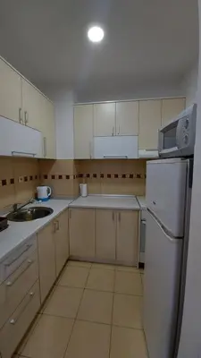 a kitchen with white cabinets and a sink and a refrigerator at Apartman Kasija in Jagodina