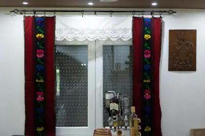 a window with red curtains with flowers on it at Vila Dimitrijevic Lisine in Despotovac