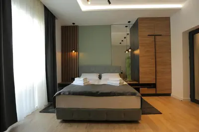 a bedroom with a large bed and a mirror at Bonanza Apartments in Niš