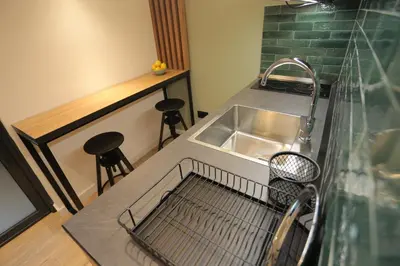 a kitchen with a sink and a counter with stools at Bonanza Apartments in Niš